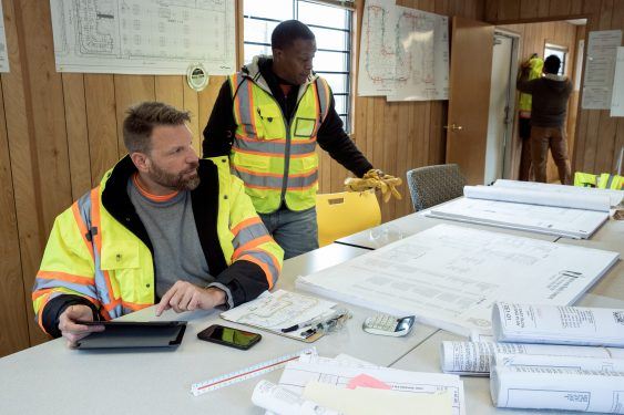 Construction workers sitting at a table with construction plans.