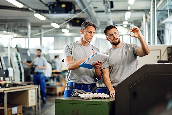 Two workers examining finished products and writing notes in facility.