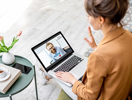 A woman using her laptop for an online video meeting.