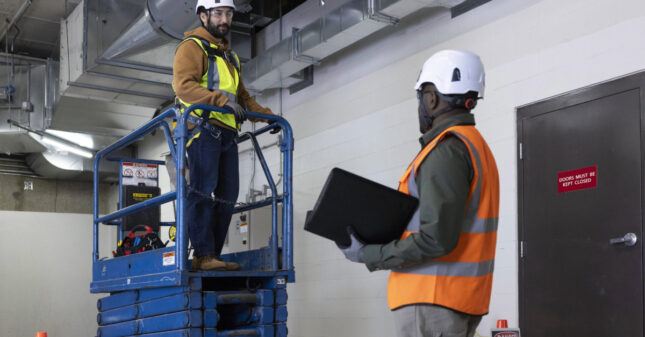 Two construction workers consult at a job site.